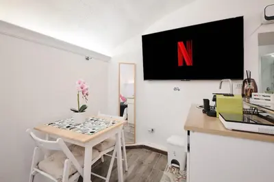 a kitchen with a table and a tv on the wall at Casa Chicca Monti - Idromassaggio 900 m Colosseo in Rome