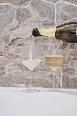 a bottle of white wine being poured into two wine glasses at Casa Chicca Monti - Idromassaggio 900 m Colosseo in Rome