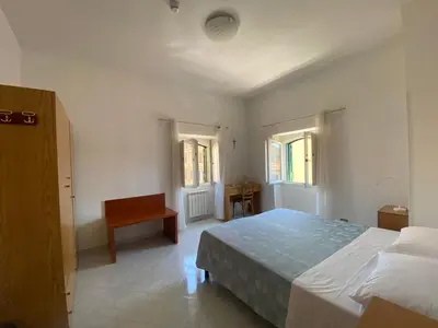 a bedroom with a bed and a desk and windows at Casa per Ferie Suore Salesiane dei Sacri Cuori in Rome
