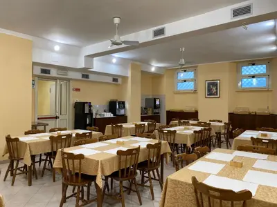 a dining room with tables and chairs and a kitchen at Casa per Ferie Suore Salesiane dei Sacri Cuori in Rome