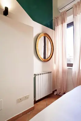 a bedroom with a bed and a mirror and a window at TrastevereHome - Secret Balcony in the Heart of Rome Trastevere in Rome