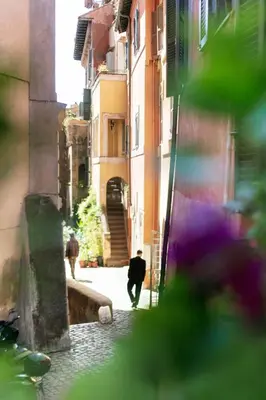 a man walking down a street in an alley at TrastevereHome - Secret Balcony in the Heart of Rome Trastevere in Rome
