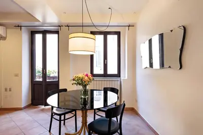 a dining room with a table and chairs and a mirror at TrastevereHome - Secret Balcony in the Heart of Rome Trastevere in Rome