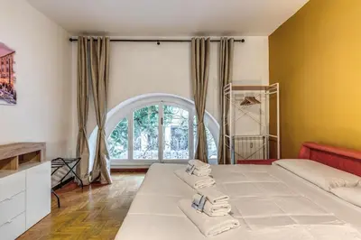 a bedroom with two beds and a large window at Dimora Lunetta - Modern Flat in Vatican District in Rome