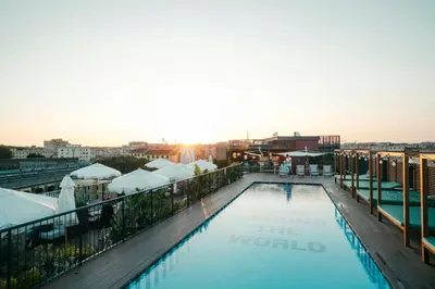a pool on the roof of a building with the sunset at The Social Hub Rome Extended Stay in Rome