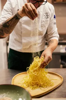 a man in a kitchen preparing noodles on a cutting board at The Social Hub Rome Extended Stay in Rome