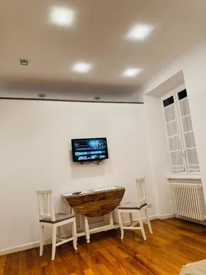 a room with two chairs and a table with a television on the wall at Suite Eroi in Rome