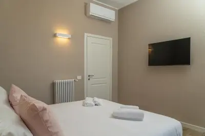 a bedroom with a white bed with a tv on the wall at Penthouse Vado Collection in Rome