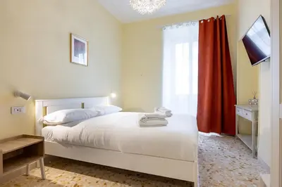 a bedroom with a white bed with a red curtain at Casa Minieri - Viale Mazzini - San Pietro in Rome