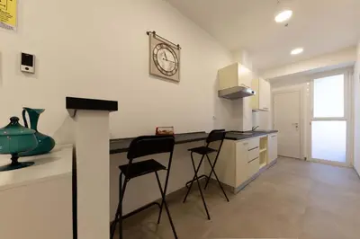 a kitchen with two chairs and a counter with a clock on the wall at auntieshouseroma in Rome