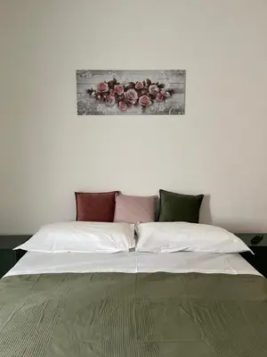 a bed with white sheets and pink flowers on the wall at The Rose Apt in Rome