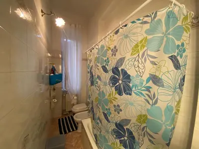 a bathroom with a shower curtain with flowers on it at Casa Bianca room 16 in Rome
