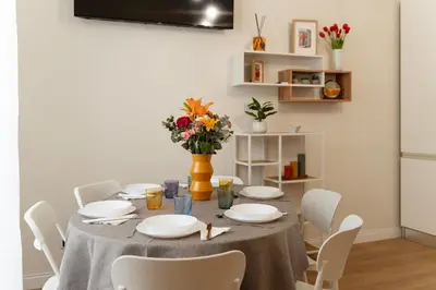 a dining room table with white chairs and a vase with flowers at PictaDomus-Albus, Metro Furio Camillo in Rome