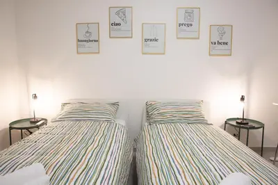 two beds in a room with pictures on the wall at Sunny's Suite - 8min from Colosseum in Rome