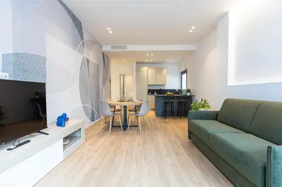 a living room with a green couch and a kitchen at Amazing Tacito in Rome