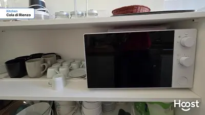 a microwave on a shelf with cups and plates at Rienzo Charme Apartment in Rome