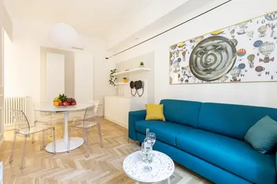 a living room with a blue couch and a table at Hostly-Puccini Luxury Home-Near Colosseum & Trevi in Rome