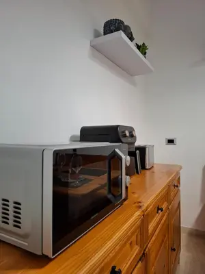 a microwave sitting on top of a wooden counter at Rome Lumina - Bilocale luminoso vicino Metro C, 6 fermate dal Colosseo in Rome
