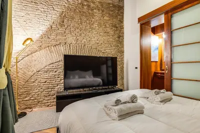 a bedroom with a brick wall with a bed and a flat screen tv at Fico Giallo - Piazza Navona Apartment in Rome