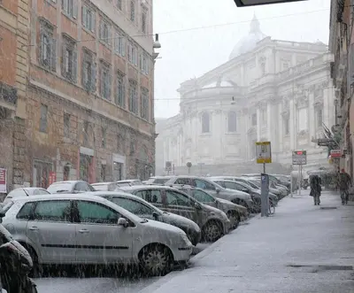 a snow covered city street with cars parked at Hotel Verona Rome in Rome