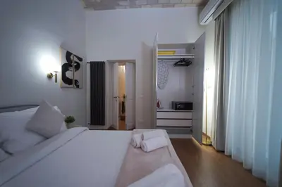 a bedroom with a large white bed and a hallway at Bruno Domus Colosseo in Rome