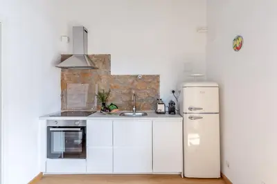 a white kitchen with a refrigerator and a sink at Hostly-Light and Wood Rome Midtown-Near Trevi in Rome