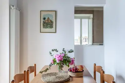 a dining room table with a vase of flowers and fruit on it at Hostly-Light and Wood Rome Midtown-Near Trevi in Rome