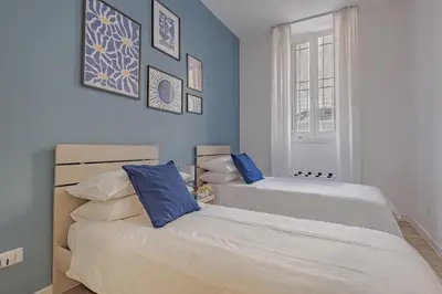 two beds in a bedroom with blue walls at B&F Home Vatican Stay in Rome