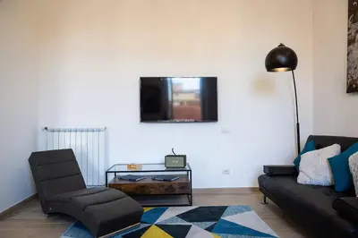 a living room with a couch and a chair and a tv at Iron Apartment Santa Maria in Rome