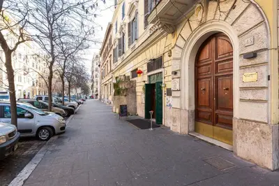 a street with cars parked next to a building with a wooden door at Iron Apartment Santa Maria in Rome