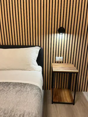 a bedroom with a bed and a wooden wall at Tiburtina Urban Rooms in Rome