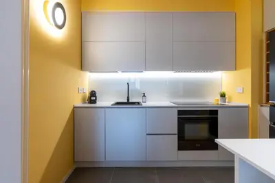 a kitchen with white cabinets and yellow walls at Sotto al letto del Papa - Borgo Pio - Vaticano in Rome