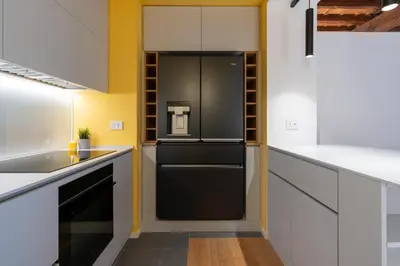 a black refrigerator in a kitchen with white cabinets at Sotto al letto del Papa - Borgo Pio - Vaticano in Rome