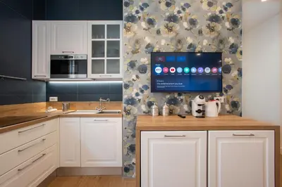 a kitchen with white cabinets and a tv on a wall at Design Home - Vicino il centro in Rome