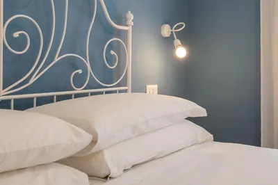 a bed with white pillows and a blue wall at Design Home - Vicino il centro in Rome