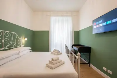 a bedroom with green walls and a bed with towels at Design Home - Vicino il centro in Rome