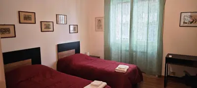 a bedroom with two beds with red sheets and a window at San Peter's Gates in Rome