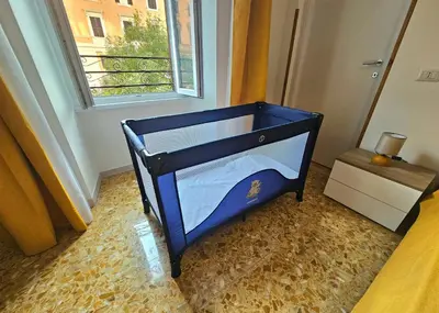 a blue crib in a room with a window at Costantino Imperatore Apt in Rome
