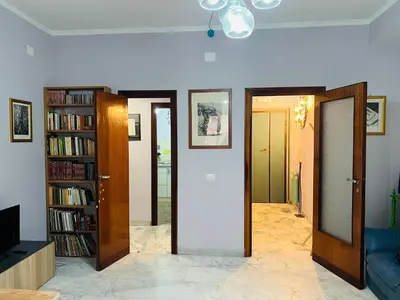 a living room with two doors and a book shelf at La Porta del Perugino - near the Vatican in Rome