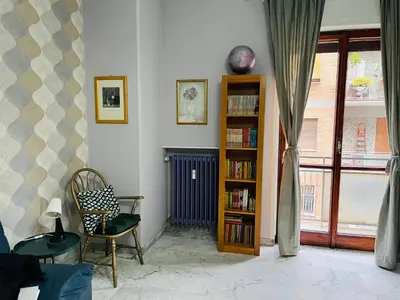 a living room with a book shelf and a chair at La Porta del Perugino - near the Vatican in Rome
