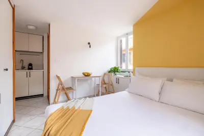a bedroom with a white bed and a kitchen at Panieri Apt - Homkeey Apartments in Rome