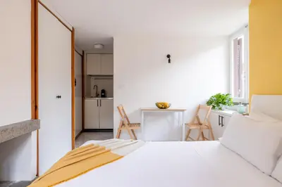 a bedroom with a white bed and a kitchen at Panieri Apt - Homkeey Apartments in Rome