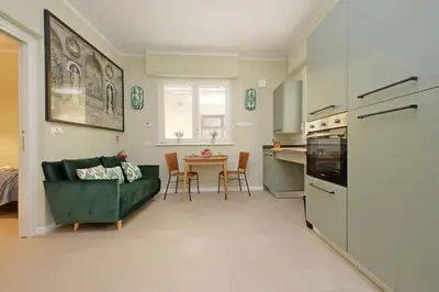 a living room with a green couch and a kitchen at Gioia's Flat in Rome