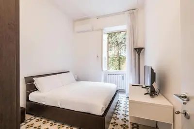 a bedroom with a bed and a tv and a window at iFlat Mid-Century Modern Vatican Apartment in Rome