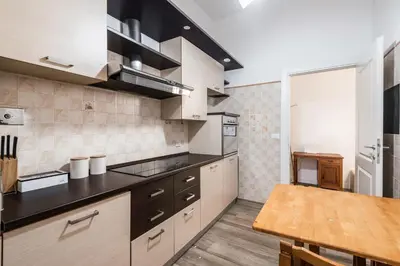 a kitchen with white cabinets and a wooden table at iFlat Mid-Century Modern Vatican Apartment in Rome