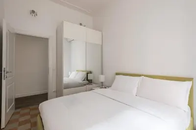 a bedroom with a large white bed and a mirror at iFlat Mid-Century Modern Vatican Apartment in Rome