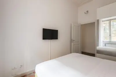 a white bedroom with two beds and a flat screen tv at iFlat Mid-Century Modern Vatican Apartment in Rome