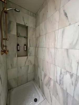 a bathroom with a shower with white marble tiles at Residenza Lucullo in Rome