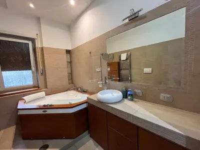a bathroom with a sink and a tub and a mirror at Charm Apartment & Relax Jacuzzi Roma-Gemelli in Rome