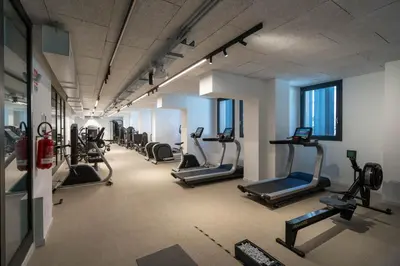 a gym with a row of treadmills and elliptical machines at AureaLiving - Sage luxury apt with Air Conditioning, Fast Wifi and free Gym in Rome